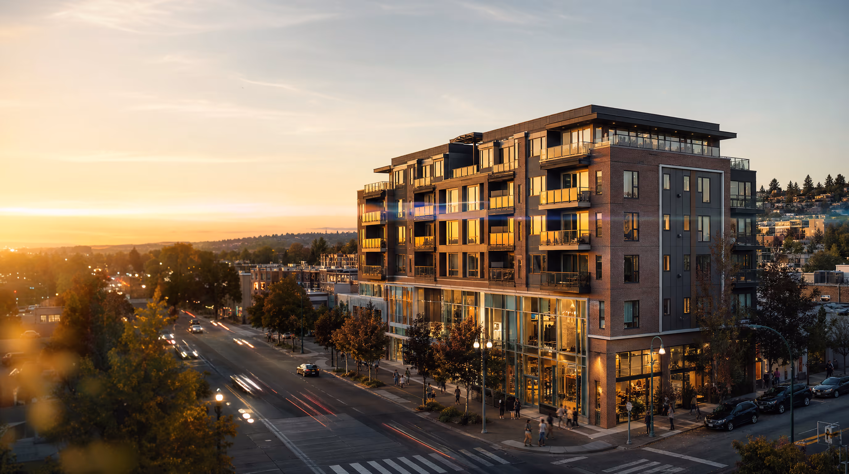 Aerial view of a multifamily residential development at dusk, lights coming on across the buildings